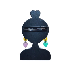 tył broszki w tym samym kształcie, jednolicie czarny z widocznym poziomym zapięciem agrafkowym pośrodku oraz zwisającymi pastelowymi zawieszkami‑sercami na białym tle